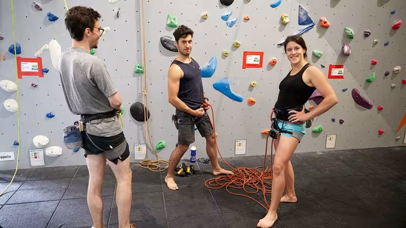 2 men and 1 woman climbers preparing ropes to climb